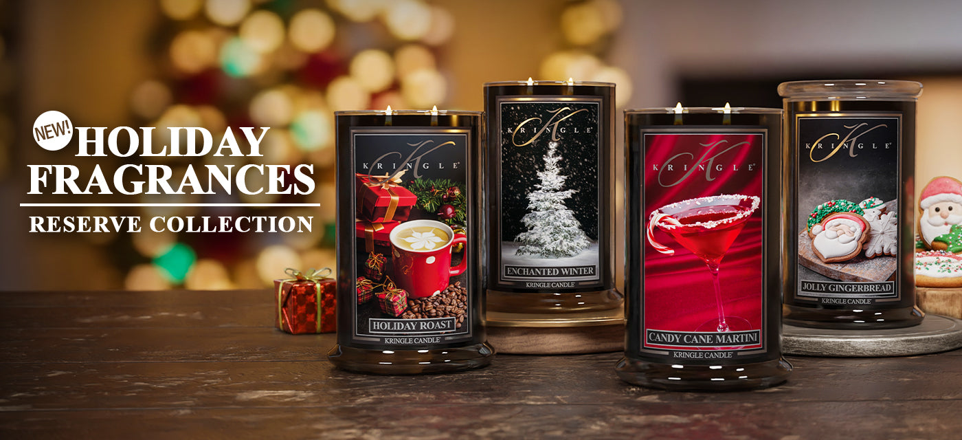 Four candles from the Reserve Collection with holiday fragrances on a wooden surface.
