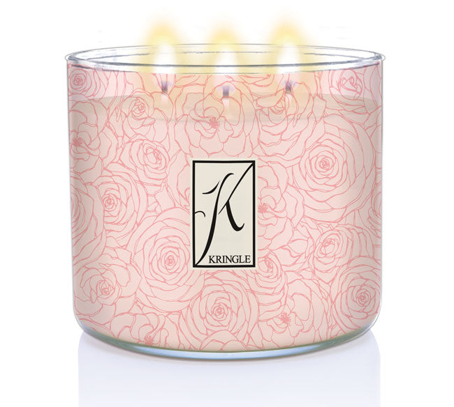 White candle with pink rose pattern in a glass jar, labeled "Kringle," with five flames lit on top.