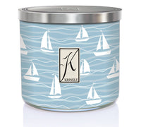 A candle in a metal tin with a light blue design of sailboats and waves. The label reads "Kringle" with a stylized "K."