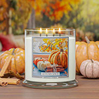 Kringle Candle Autumn Spice 4-wick lit candle with pumpkins and cinnamon sticks on a wooden surface.