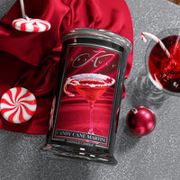 Kringle Candle with a red and white candy cane martini design on a gray surface with festive decor.