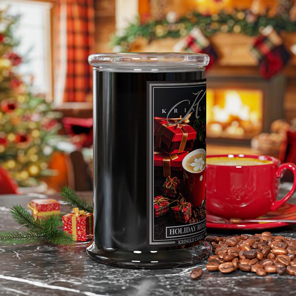 Decorative candle with a Christmas theme on a table with coffee beans and a red mug.