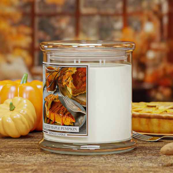 Candle jar with a pie-themed label on a wooden surface with pumpkins and pies in the background