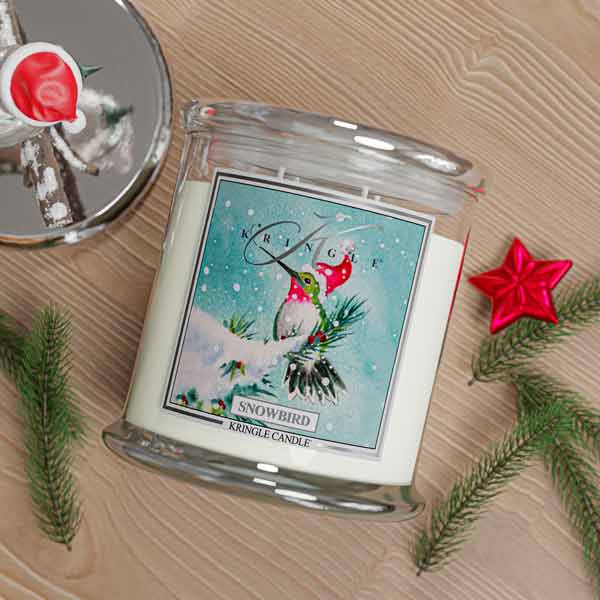 Kringle Candle Snowbird 4-wick candle with Christmas decorations on a wooden surface