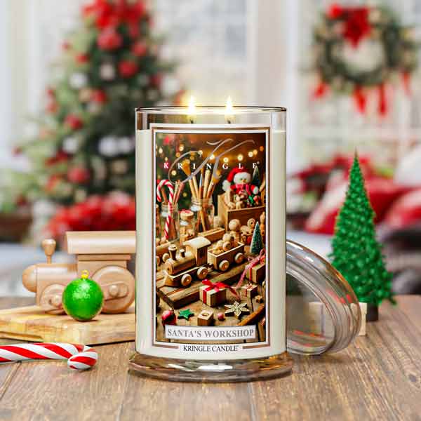 Decorative candle with Christmas-themed design on a wooden surface, surrounded by festive decorations.