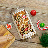 Decorative candle with Santa's Workshop design on a wooden surface with Christmas decorations.