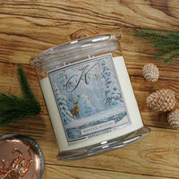 Kringle Candle winter wood scented candle on a wooden surface with decorative elements.