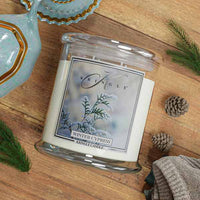 Kringle Candle Winter Cypress candle on a wooden surface with decorative elements.