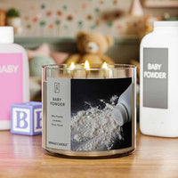 A three-wick lit candle in a clear glass jar with a classic powder-themed label. The candle’s wax is soft white, and all three wicks are burning.