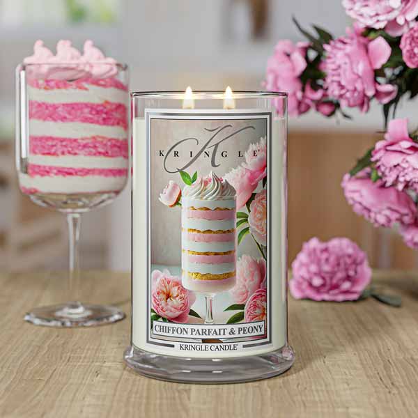 A lit candle labeled "Chiffon Parfait & Peony" with pink floral design, set on a countertop in a pink-themed kitchen.