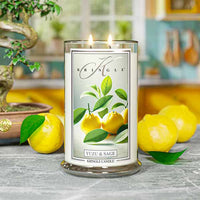 A lit Kringle candle labeled "Yuzu & Sage" on a table, with a vibrant kitchen background featuring yellow accents.