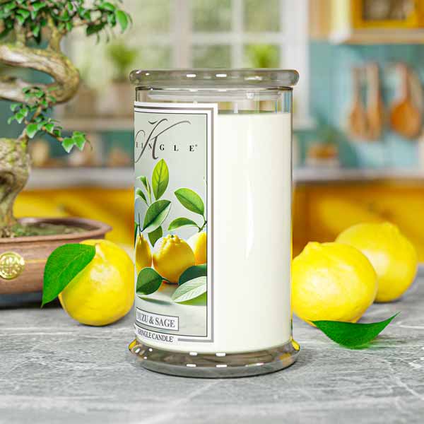 Glass jar candle with label showing yellow yuzu fruits and green leaves. Text: "Yuzu & Sage," "Kringle Candle."