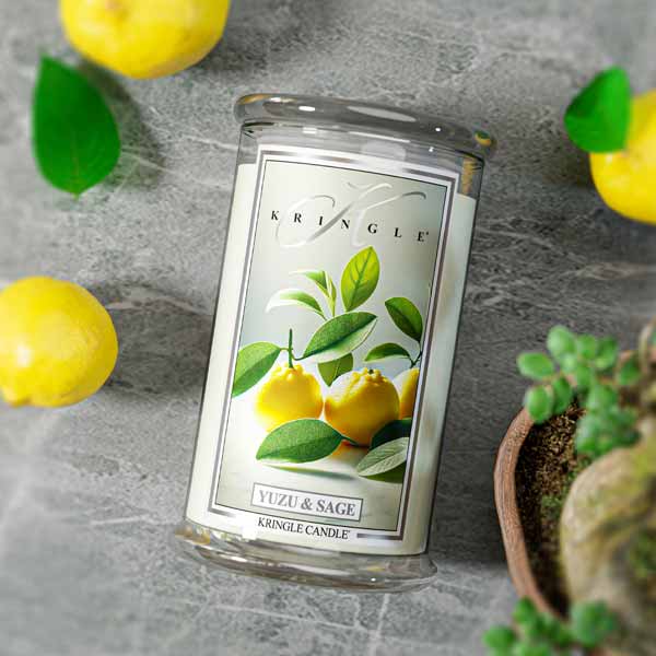 Glass jar candle with label showing yellow yuzu fruits and green leaves. Text: "Yuzu & Sage," "Kringle Candle."