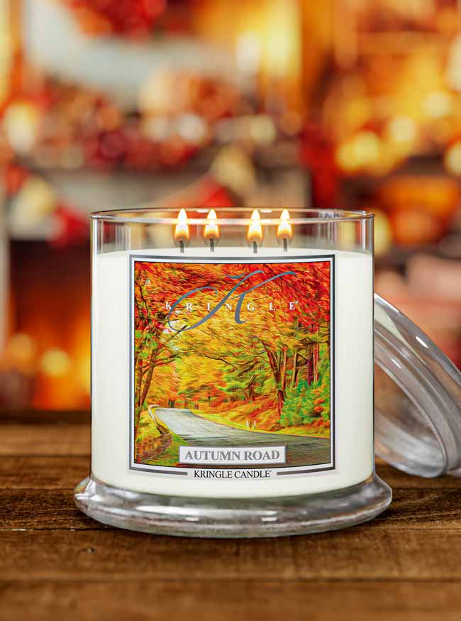 Kringle Candle autumn-themed Autumn Road lit candle with a blurred background