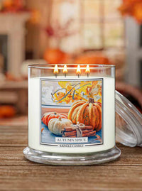 Four-wick candle labeled 'Autumn Spice' with a pumpkin-themed label on a wooden surface.
