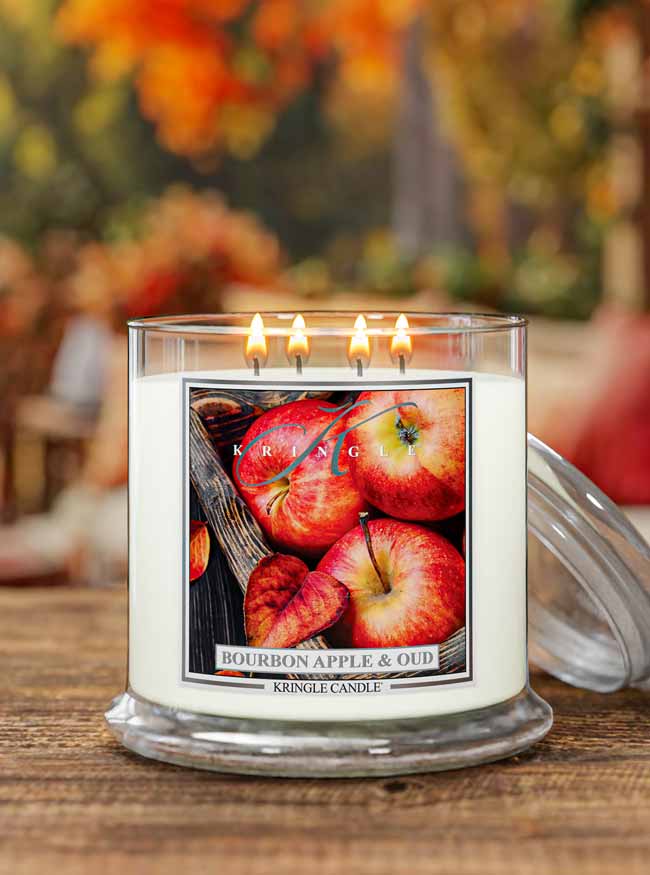 Kringle Candle with 4-wick extra large Bourbon Apple & Oud candle featuring apples in an autumn leaves background.