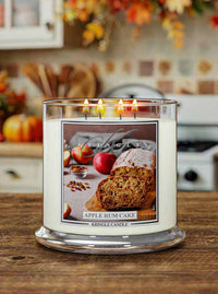 Lit XL 4-Wick candle labeled "Apple Rum Cake" with an image of sliced apple cake, apples, and spices.