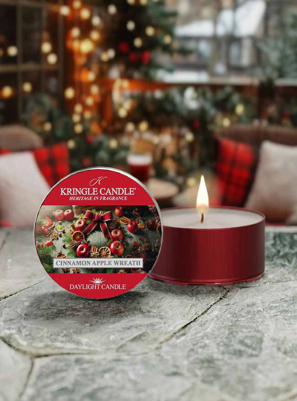 Kringle Candle daylight candle with packaging on a stone surface, Christmas tree and decorations in the background