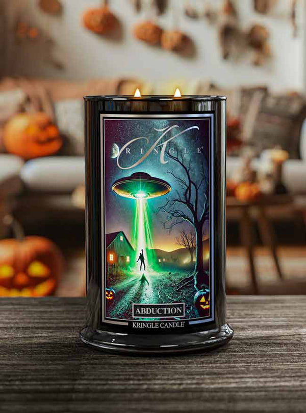 Kringle Candle with alien abduction design on a table with pumpkins in the background