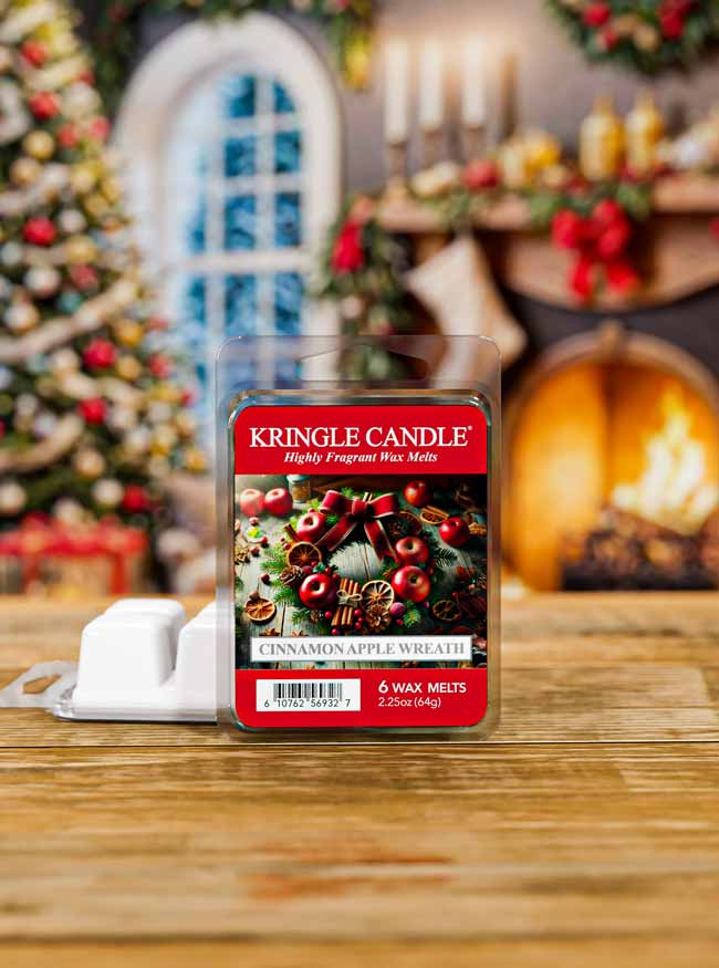 Kringle Candle Cinnamon Apple Wreath wax melt packaging on a wooden surface with a festive background.