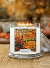 Kringle Candle lit Amber wood candle with a scenic label on a wooden surface.