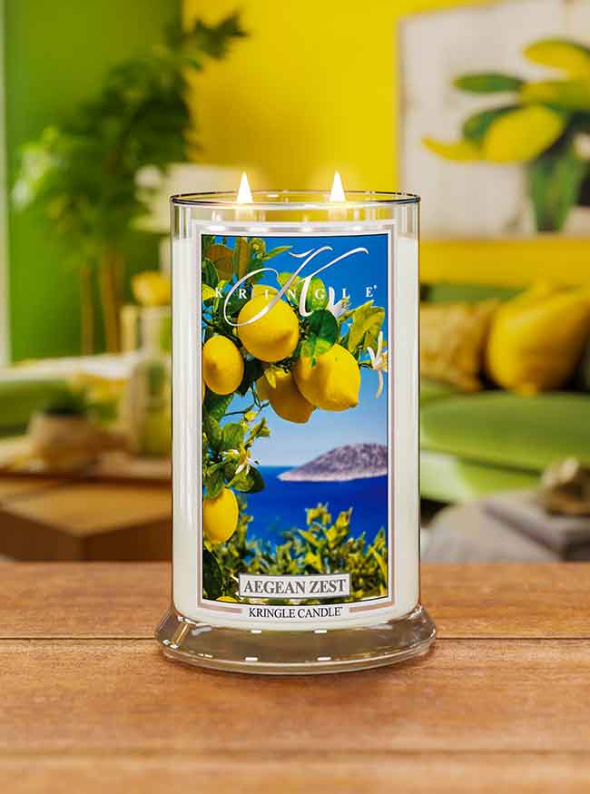 Lit candle labeled "Aegean Zest" with lemons and ocean scene, set in a colorful room with green, yellow decor.