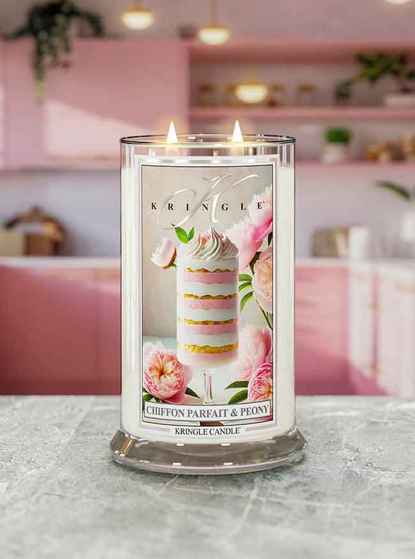 A lit candle labeled "Chiffon Parfait & Peony" with pink floral design, set on a countertop in a pink-themed kitchen.