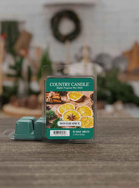 Package of "Country Candle" Winter Spice wax melts with images of oranges and cinnamon on a wooden table.