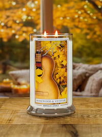 Lit 2-wick candle in clear jar; label shows guitar and yellow leaves. Fragrance: Rosewood & Vetiver.