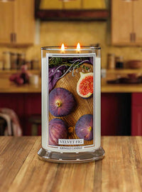 Lit Velvet Fig 2-wick candle. Label shows whole and half figs on wood with herbs.