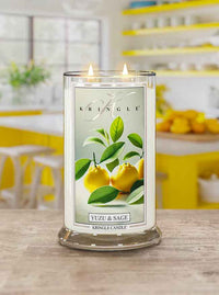 A lit Kringle candle labeled "Yuzu & Sage" on a table, with a vibrant kitchen background featuring yellow accents.