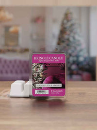 Kringle Candle wax melts labeled "Sugar Plum & Myrrh" on a table, with a blurry Christmas tree in the background.