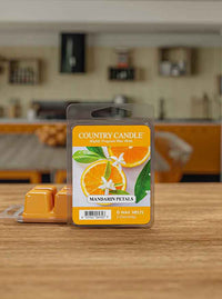 Package of "Country Candle" Mandarin Petals wax melts on a wooden table, with a kitchen in the background.