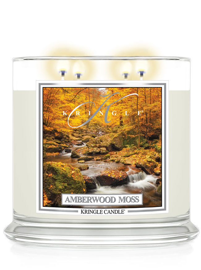 Lit XL 4-wick candle, Amberwood Moss. Label features an autumn forest with a flowing stream among mossy rocks.