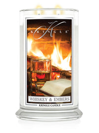 Lit 2-wick candle with label depicting a fireplace, whiskey glass, and book. Fragrance: Whiskey & Embers.
