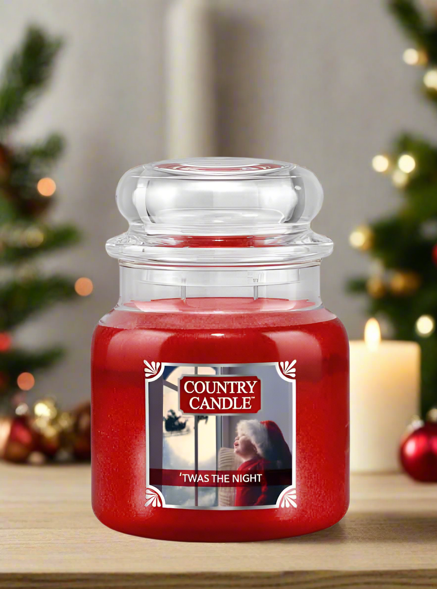 Red candle jar labeled 'Country Candle' with a Christmas-themed label on a wooden surface.