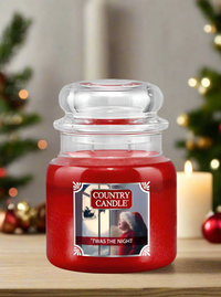 Red candle jar labeled 'Country Candle' with a Christmas-themed label on a wooden surface.