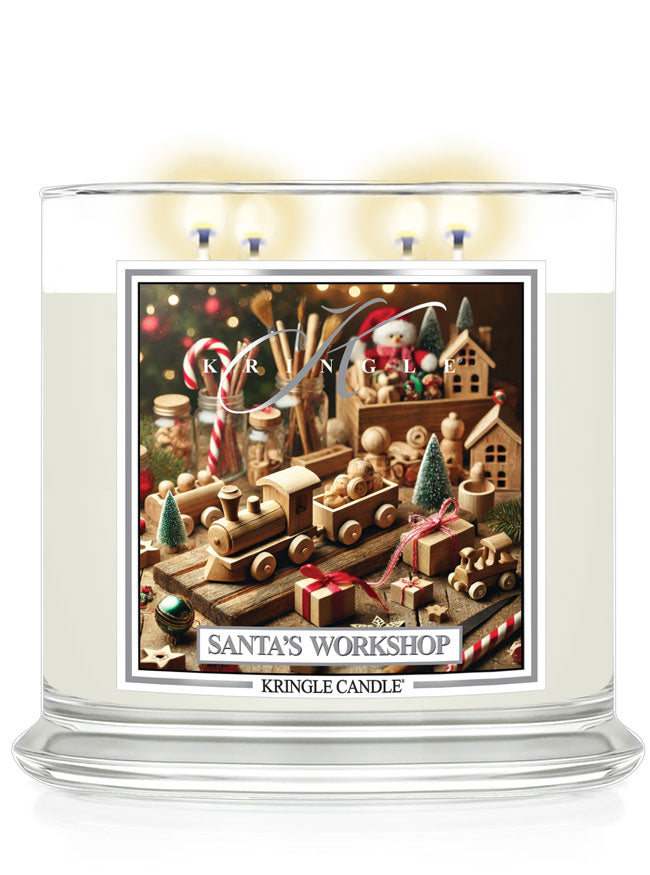 Clear glass candle with four wicks, featuring a Santa's Workshop label decorated with wooden toys and festive elements.