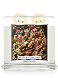 Clear glass candle with four wicks, featuring a Santa's Workshop label decorated with wooden toys and festive elements.
