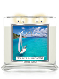 A candle labeled "Sea Salt & Bergamot" with an image of a sailboat on turquoise waters under a blue sky.