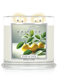 A white three-wick candle labeled "Yuzu & Sage" with an image of yellow yuzu fruits and green leaves on the side.