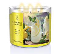 A three-wick lit candle in a clear glass jar with a refreshing drink-themed label. The candle’s wax is bright yellow, and all three wicks are burning.