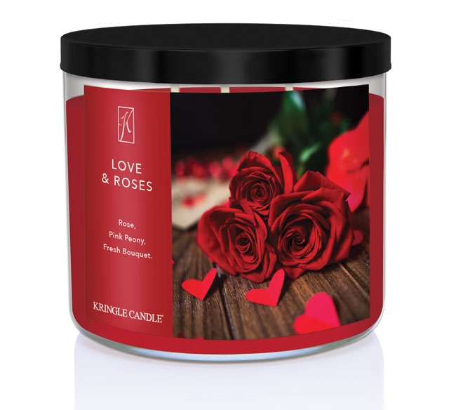 A three-wick candle in a clear glass jar with a black lid and a romantic floral-themed label. The label features a close-up of red roses on a wooden surface with scattered red heart-shaped confetti. The candle’s wax is deep red, and the wicks are unlit. The scent notes listed are rose, pink peony, and fresh bouquet.