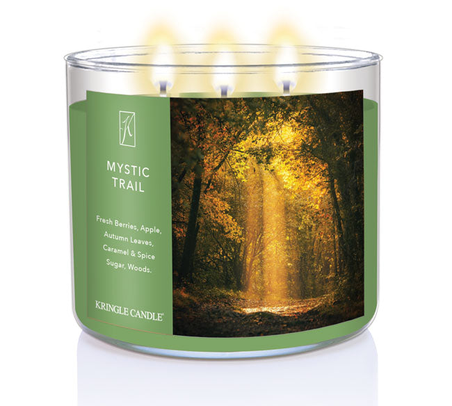 A three-wick lit candle in a clear glass jar with a forest-inspired label. The candle’s wax is an earthy green, and all three wicks are burning.