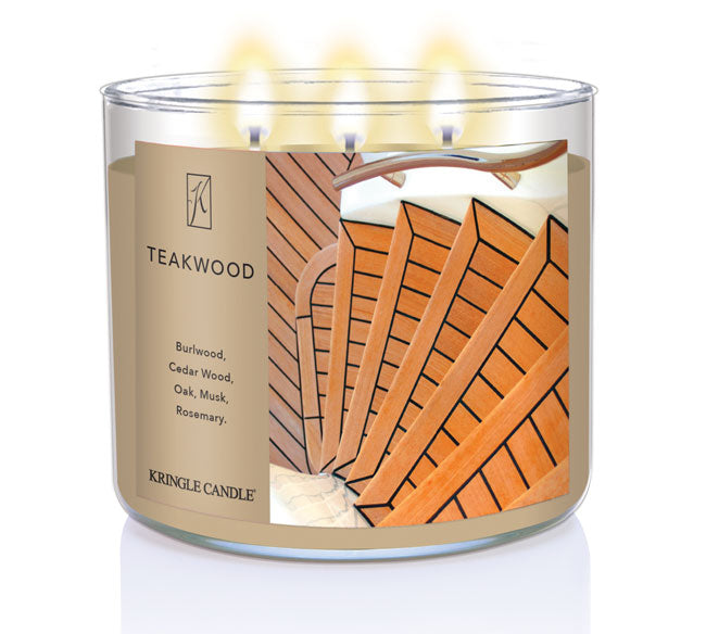 A three-wick lit candle in a clear glass jar with a sophisticated wood-themed label. The candle’s wax is rich brown, and all three wicks are burning.