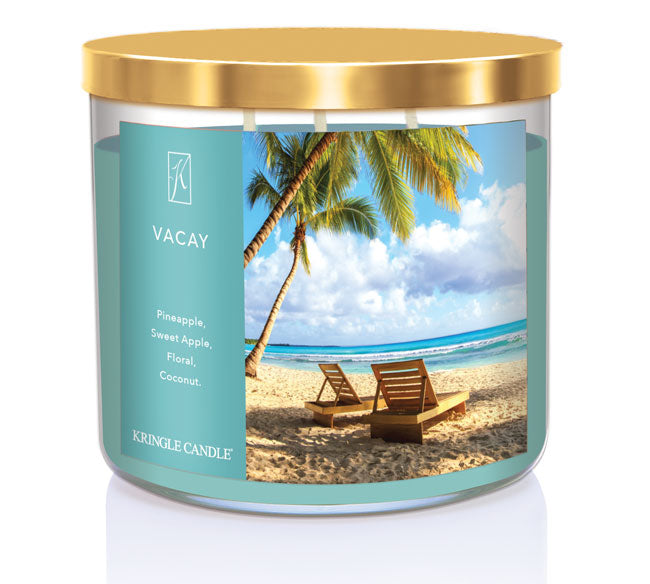 A three-wick candle in a clear glass jar with a silver lid and a tropical vacation-themed label. The label features a scenic view of a beachside resort, with a clear blue ocean and palm trees swaying in the breeze. The candle’s wax is sunny yellow, and the wicks are unlit. The scent notes listed are pineapple, apple, florals, and coconut.