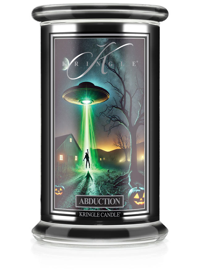 Unlit Halloween candle labeled "Abduction." The label shows a UFO abducting a person near a farmhouse with glowing lights.