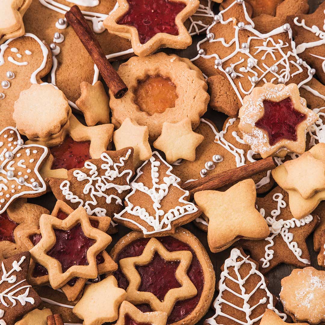 Assorted decorated cookies including stars, snowflakes, and cinnamon sticks on a white background