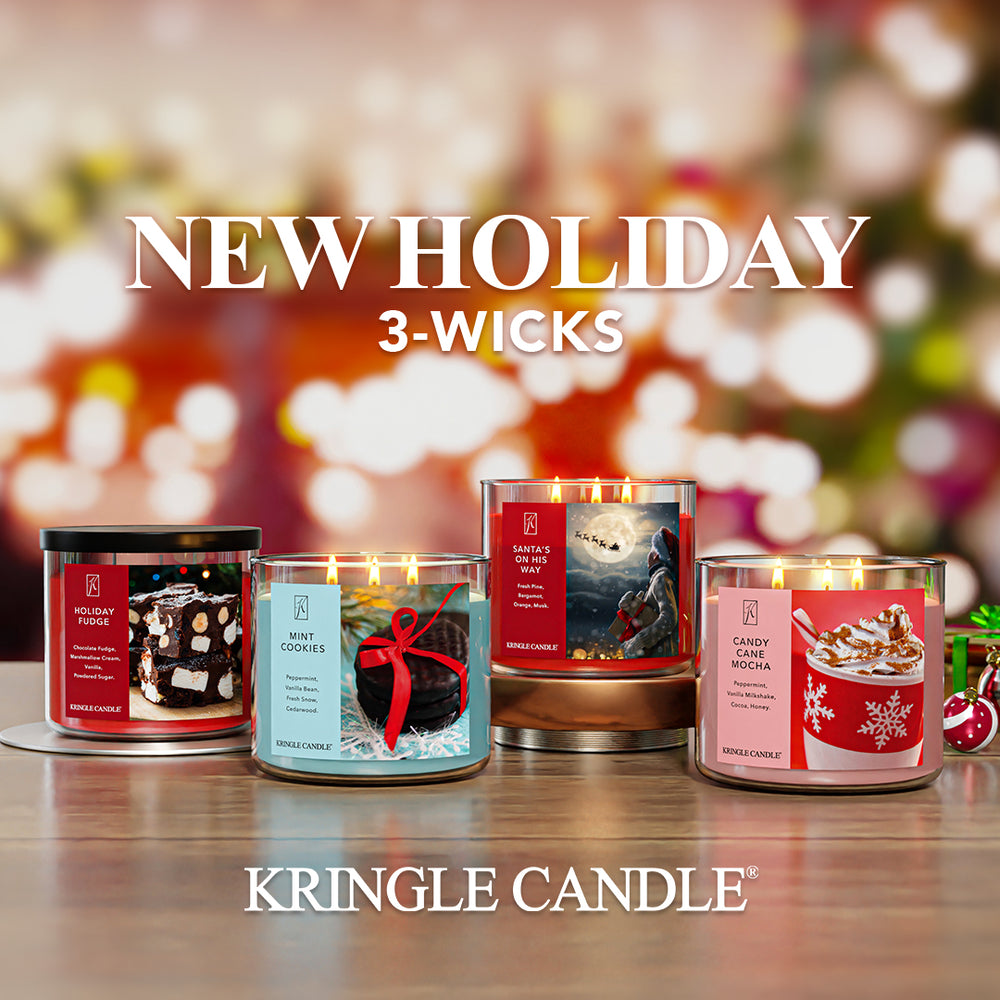 Four Kringle Candle candles with festive labels on a blurred holiday background