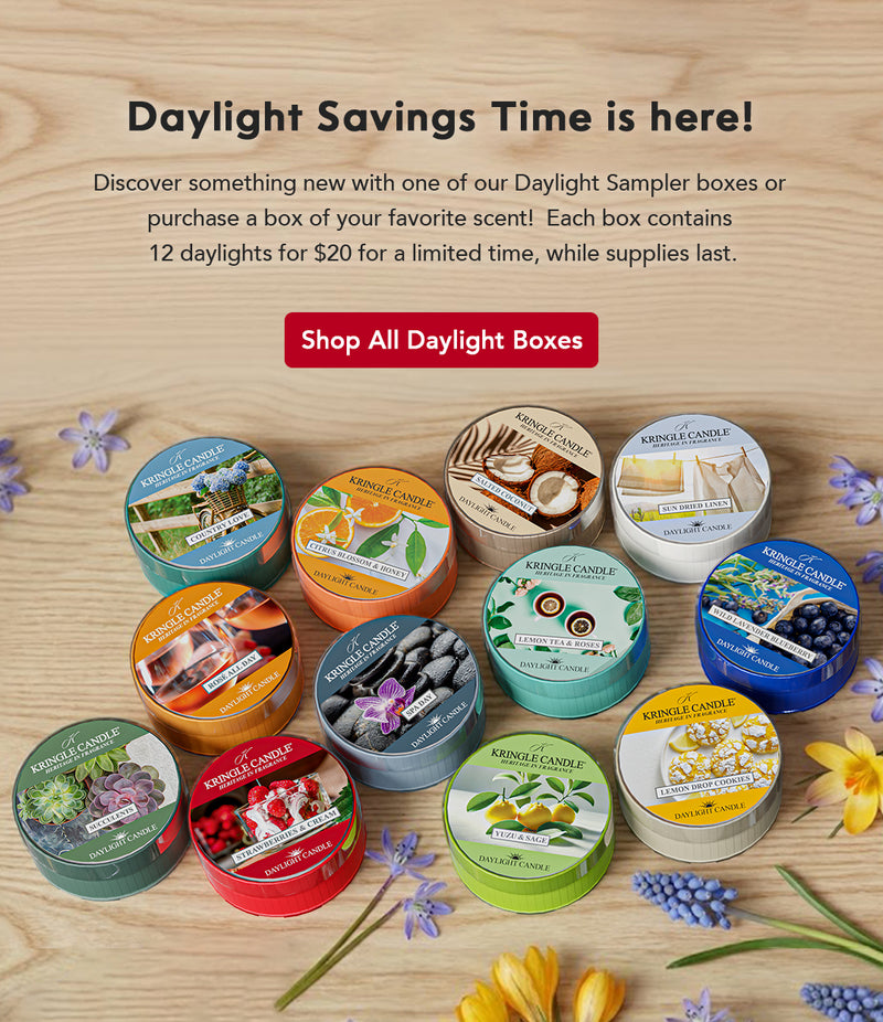 Collection of Kinkade candles on a wooden surface with promotional text for Daylight Savings Time.